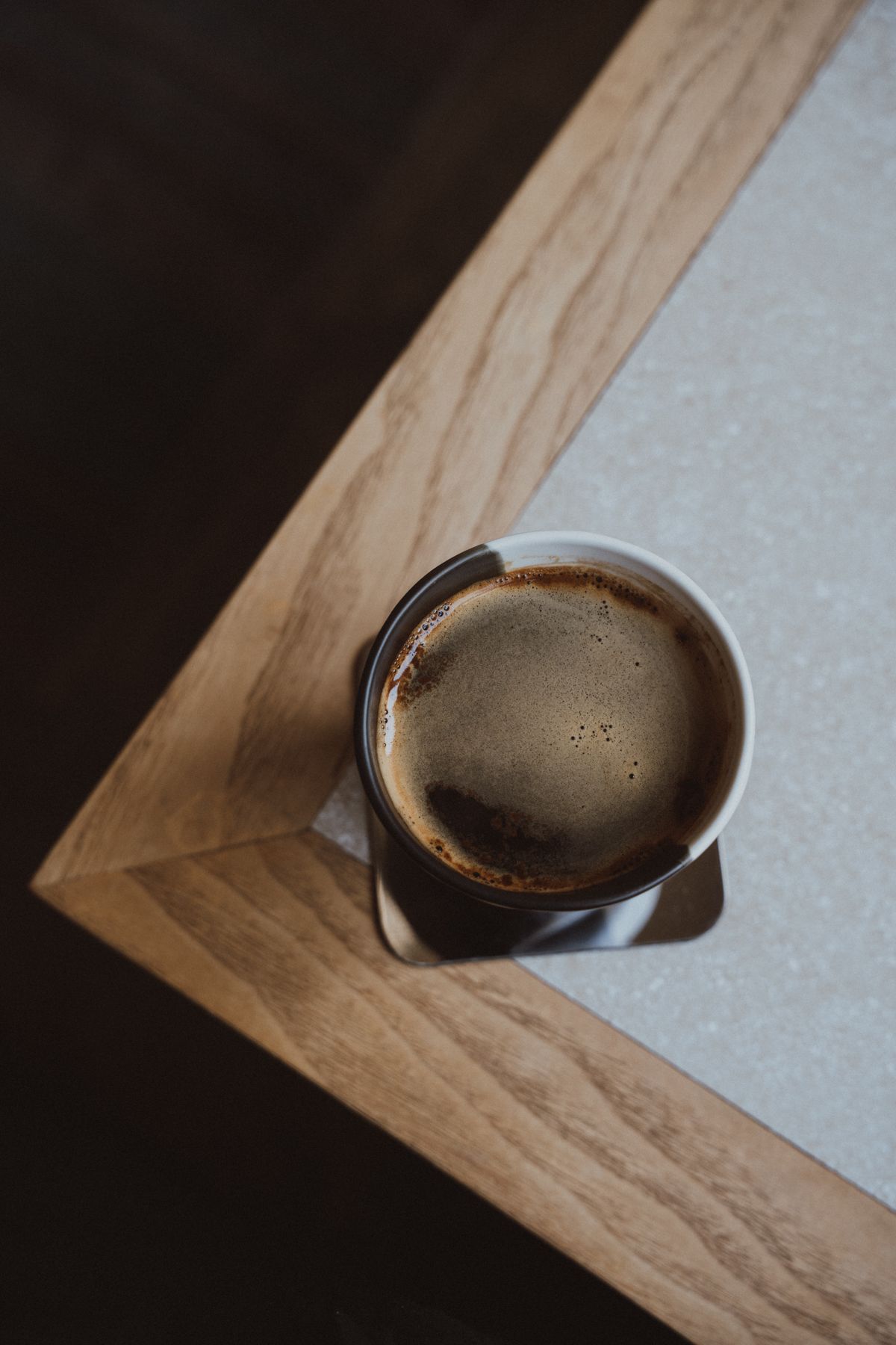 木のテーブルに置かれたミニマルなコーヒーカップ